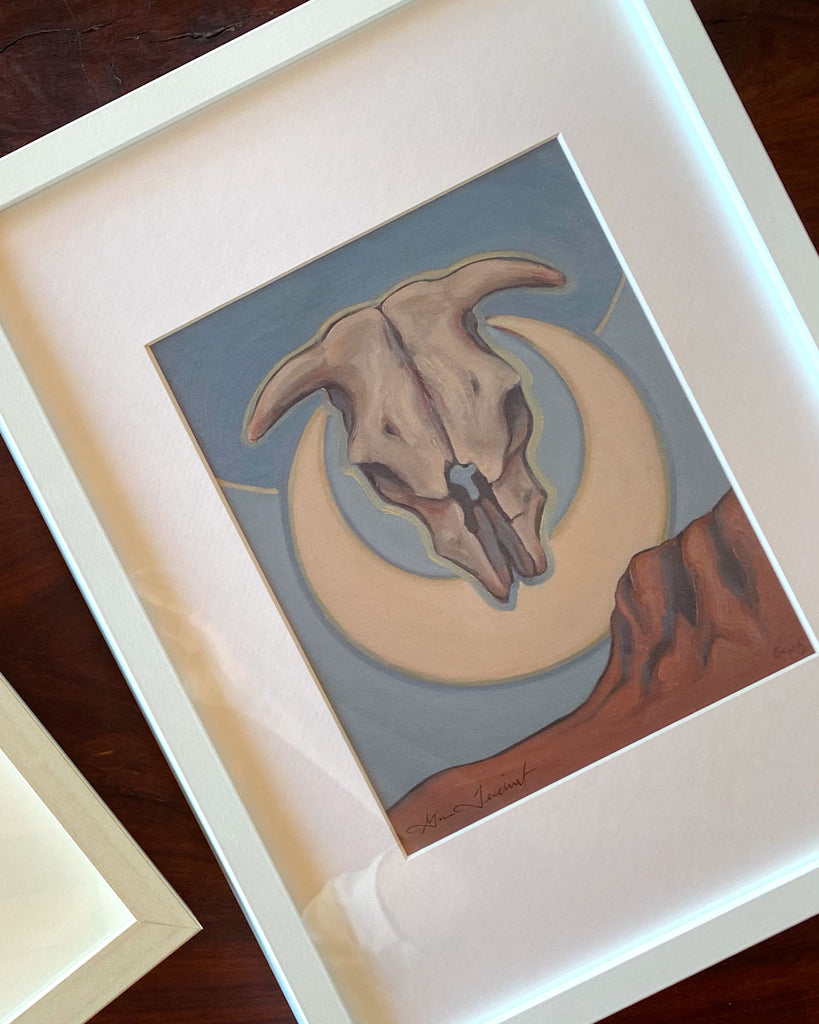 Print of a cow sull and cresent moon in a white frame