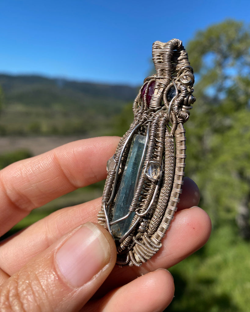 woman holding a wire wrapped crytal necklace with aqua blue and clear stones