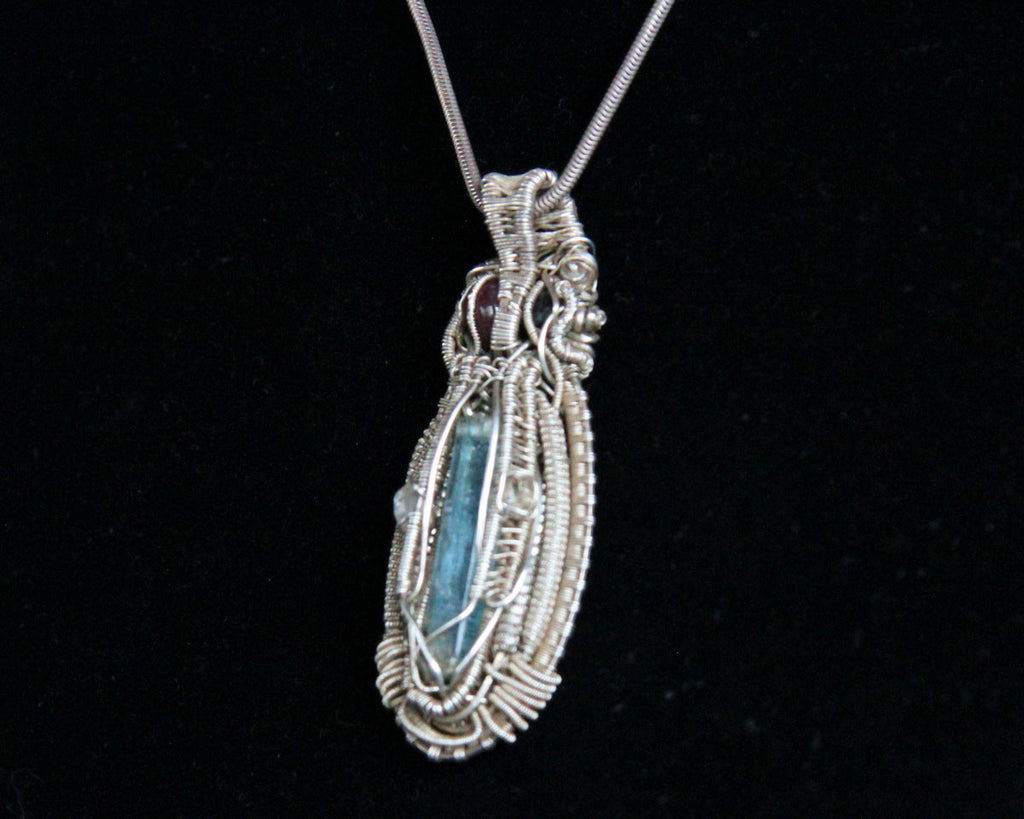 Blue crystal pendant wrapped in silver wire on a black background